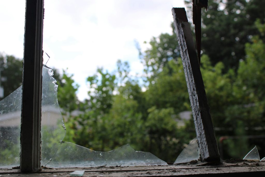 a broken glass window with trees in the background