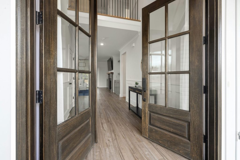 Entrée spacieuse avec d'élégantes portes doubles en bois menant à un intérieur moderne.