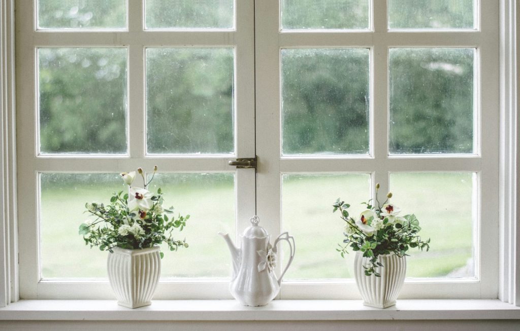 a white teapot and two flower vases on a glass pane